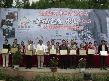 现场为受助村庄代表授予书屋铜牌